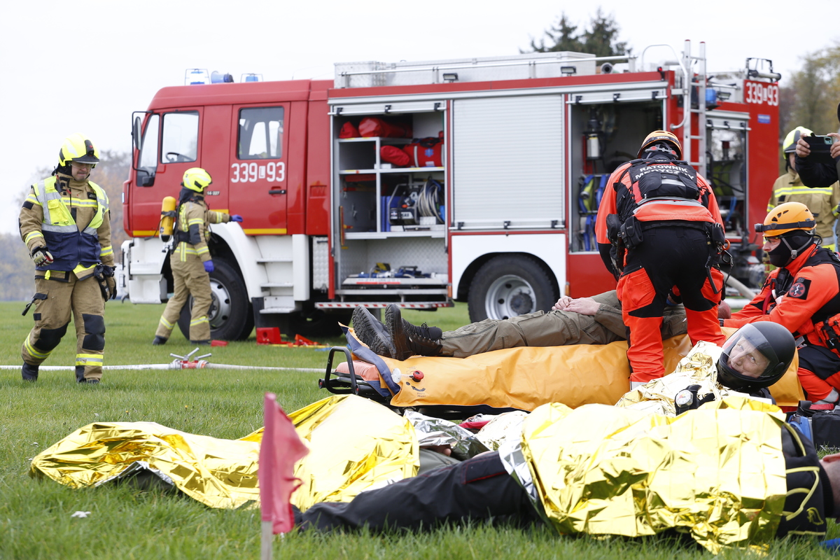 Strażacy i ratownicy medyczni udzielają pomocy poszkodowanym w wypadku lotniczym.