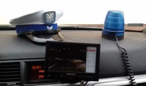 kokpit policyjnego radiowozu, na którym leży czapka policyjna