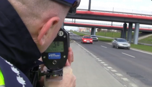 fot. policjant sprawdzający prędkość pojazdów ręcznym miernikiem prędkości